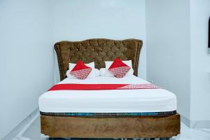 a bed with red and white pillows on it at Hotel O Stasiun Cirebon Kejaksan Near Alun Alun Cirebon Formerly Family Homestay in Cirebon