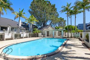 a swimming pool with palm trees and a house at Trackside Tranquility - TC522B in Solana Beach
