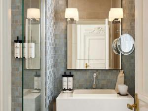 巴黎索菲特巴黎法布格酒店的浴室里有洗手池和镜子