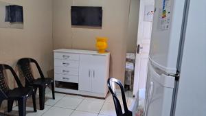 a kitchen with chairs and a white dresser and a refrigerator at Recanto da vó Maria in Ilha Rasa