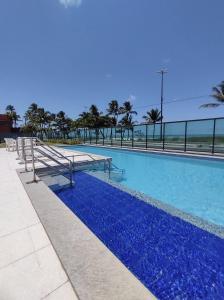 a swimming pool with blue water and palm trees at Rio Park Avenue, Espaço Familia - by TRH Home Stay in Recife