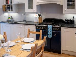 eine Küche mit einem Holztisch und einem schwarzen Herd in der Unterkunft Rose Cottage in Cardigan + 32 Fotos