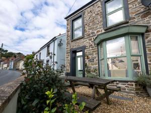 ein Steinhaus mit einer Bank davor in der Unterkunft Rose Cottage in Cardigan