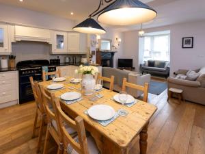 eine Küche und ein Wohnzimmer mit einem Holztisch und Stühlen in der Unterkunft Rose Cottage in Cardigan