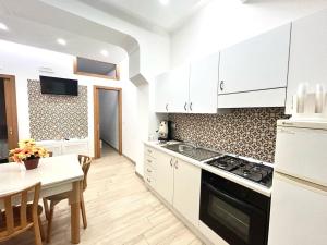 a kitchen with white cabinets and a table and a stove at La casa dei lapilli, Pompei in Terzigno