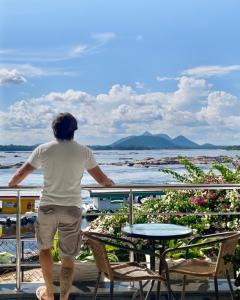 a man standing on a balcony looking at the water at LA VITRINE Hotel in São Gabriel da Cachoeira +1 photo