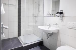 a white bathroom with a sink and a shower at Hotel Villa-Bassermann, stilvoll, 2 Min zum Schloss, schnelles WLAN & Parkplatz in Schwetzingen