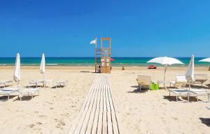 einen Sandstrand mit Liegestühlen und Sonnenschirmen und dem Meer in der Unterkunft Pet Friendly Home In Marina Di Modica in Marina di Modica