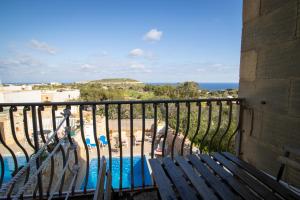 a balcony with a bench and a view of the ocean at Il figolla farmhouse in Xagħra