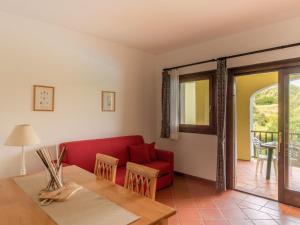 a living room with a red couch and a table at Apartment Country Village Sea VIllas by Interhome in Cuile Pazzoni