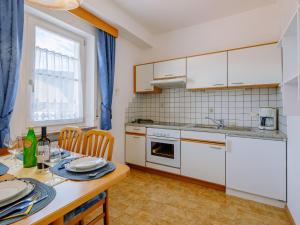a kitchen with white cabinets and a table at Apartment Rosengartenhof-1 by Interhome in Andrian