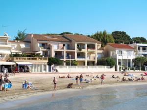 Un grupo de personas en una playa con edificios. en Apartment Baie des Lecques by Interhome, en Saint-Cyr-sur-Mer