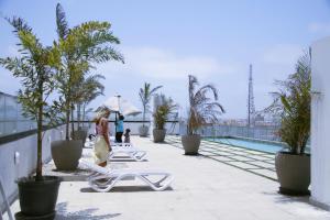 Una mujer caminando por el tejado de un hotel con un paraguas. en DakarByDays DBD011 Appartement Astou 3 chambres, en Dakar