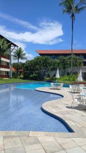 einen Pool mit Tischen und Stühlen in einem Resort in der Unterkunft Marulhos Resort by HomeTemp in Porto De Galinhas