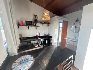 a kitchen with a black counter and a pendant light at Cabana Privativa para Casal Wind Vacance in Touros