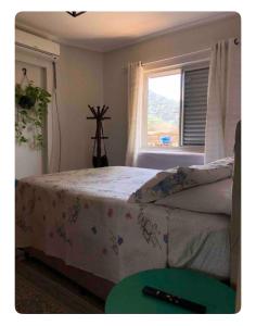 a bedroom with a bed with a table and a window at Apto Praia canto do forte in Praia Grande