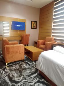 a hotel room with a bed and chairs and a tv at Ja'Oak Hotel and Suites in Benin City +12 photos