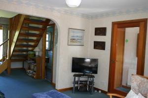 a living room with a television and a staircase at Church Cottage with sunny garden in Ayr