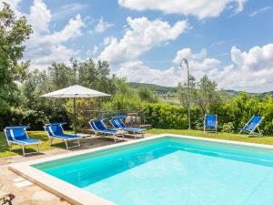 a swimming pool with chairs and an umbrella at Holiday Home Reggine-3 by Interhome in Panzano