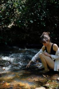 a woman sitting on a rock in a stream at Hospedaria do Feno in Brotas +89 photos