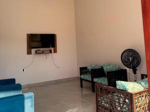 ein Wohnzimmer mit zwei Stühlen und einem Flachbildfernseher in der Unterkunft Casa Barra São Miguel in Barra de São Miguel