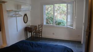 a bedroom with a bed and a window and a chair at Votre terrasse vue mer sous la vigne, un havre de paix in Ensuès-la-Redonne