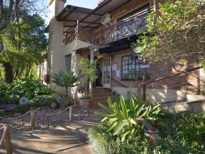 een bakstenen huis met een balkon en planten ervoor bij Autumn Breeze Manor Guest House in Graskop