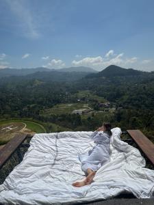 a woman laying on a blanket on top of a mountain at Sundaras Infinity Jungle Resort & Spa in Dambulla