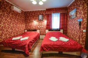 two beds in a room with red walls at Briz Hotel in Ryazan