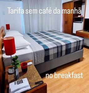 een hotelkamer met een bed en een tafel met een rode lamp bij Hotel Germânia in Joinville