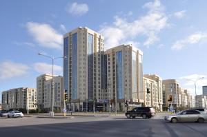 a large building with cars on a city street at Apartment Promenade EXPO in Astana