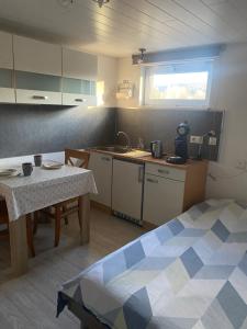 a room with a kitchen with a table and a table and a bed at Petit Studio du Horst Bach in Wimmenau
