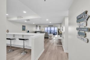 a kitchen and living room with a bar with stools at Magnificent Gulf Front Condo Located Directly on the Ocean! condo in Indian Rocks Beach