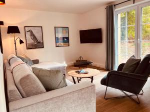 Una sala de estar con un sofá y sillas y un televisor. en Gartenhaus L - Sommerhaus 54, en Grödersby