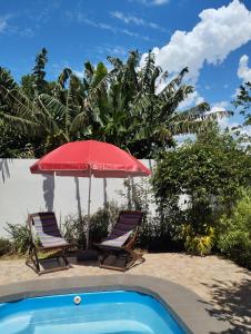 - deux chaises et un parasol rouge à côté de la piscine dans l'établissement Brisas Iguazú, à Puerto Iguazú