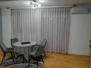 a table and chairs in a room with a curtain at Kocovski Apartment in Bitola