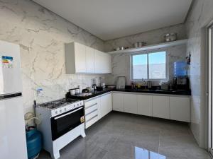 eine Küche mit weißen Schränken und einem Herd mit Backofen in der Unterkunft Casa Barra São Miguel in Barra de São Miguel
