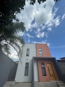 a building with yellow doors and a palm tree at LOFT ROOTS rosa in Joanópolis