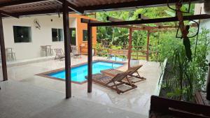 a swimming pool with a chair and a house at Casa da Farofa in Morro de São Paulo