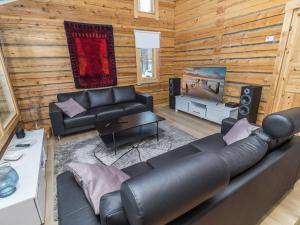 ein Wohnzimmer mit einem Ledersofa und einem Flachbild-TV in der Unterkunft Holiday Home Juohde by Interhome in Kuusamo