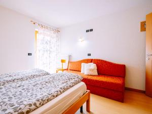 a bedroom with a bed and a red couch at Apartment Delago by Interhome in Pera