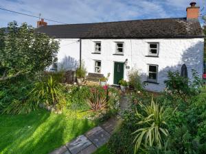 a white house with a garden in front of it at Fern Cottage in Cardigan