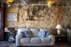 a living room with a white couch against a stone wall at Il figolla farmhouse in Xagħra