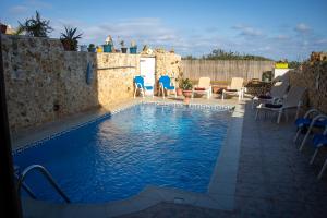 a swimming pool with chairs and a table at Il figolla farmhouse in Xagħra