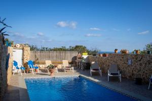 a swimming pool with chairs and a table and the ocean at Il figolla farmhouse in Xagħra
