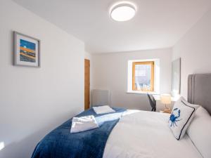 1 dormitorio con cama blanca y manta azul en Apartment Harbour Nights 7D by Interhome, en Lossiemouth