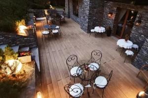 a patio with tables and chairs on a wooden deck at ECO Willa Grand Karpatia Ski&Wellness in Murzasichle