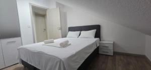 伊加洛Taksim Apartman 1的卧室里有一张白色的床，床上有两条毛巾