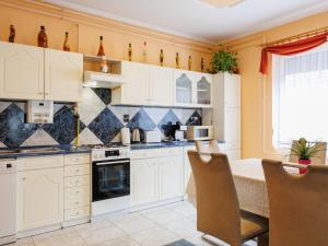 a kitchen with white cabinets and a table with chairs at Apartment Gyula by Interhome in Balatonszemes