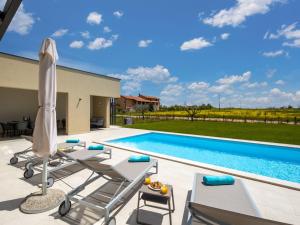 a pool with lounge chairs and an umbrella at Villa Stella & Alba by Interhome in Brtonigla